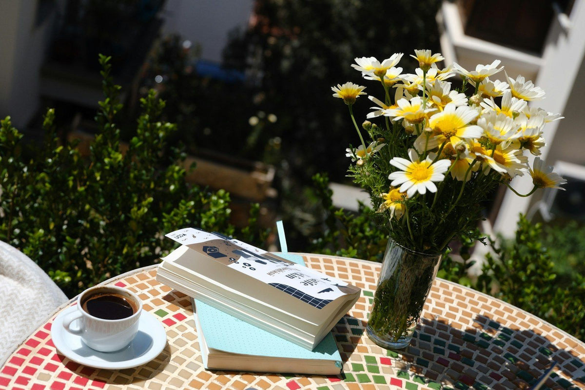 Get A Kluu books and a cup of coffee on a patio table with daisies