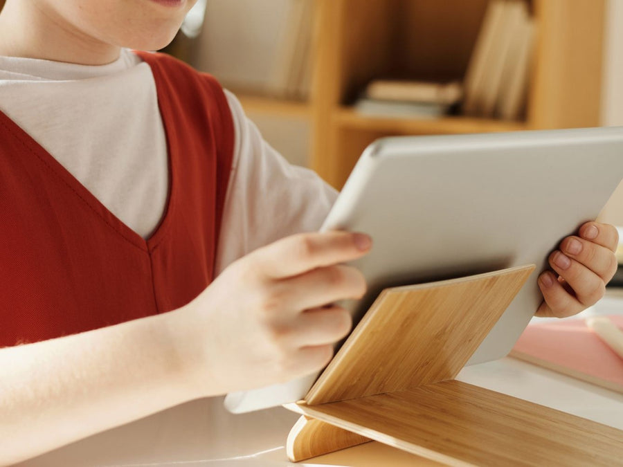A child's hands holding a tablet at a table