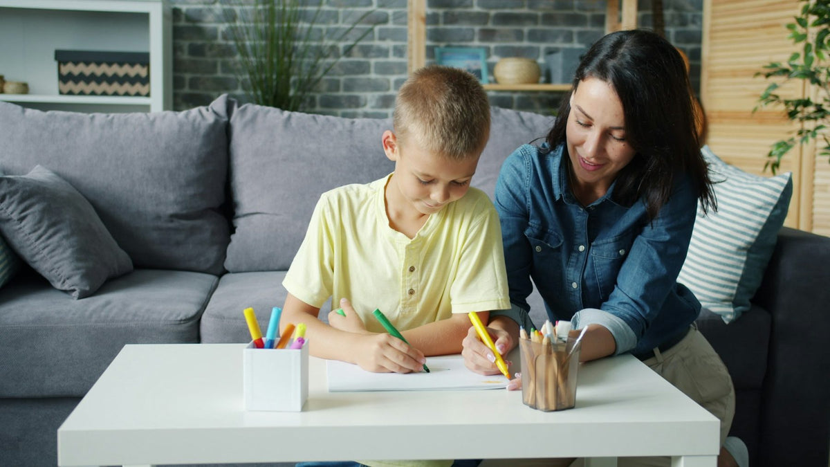 A mother and son working together at a coffee table
